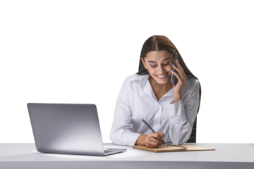 Cheerful businesswoman on phone taking notes, laptop open on desk, multitasking concept