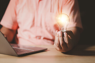 Idea innovation and inspiration concept. Hand of man holding illuminated light bulb, concept creativity with bulbs that shine glitter. Inspiration of ideas for sustainable business development.