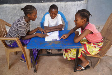 Group of African elemantary school children preparing their lesson sharing one book; concept of...