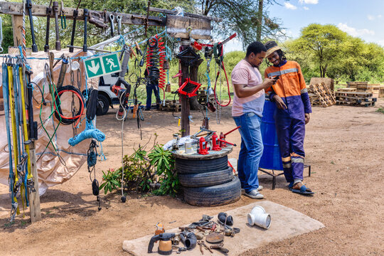 african entrepreneur, street vendor with client on the phone, selling tools, car jack, tires, cables, power tools, and various hardware