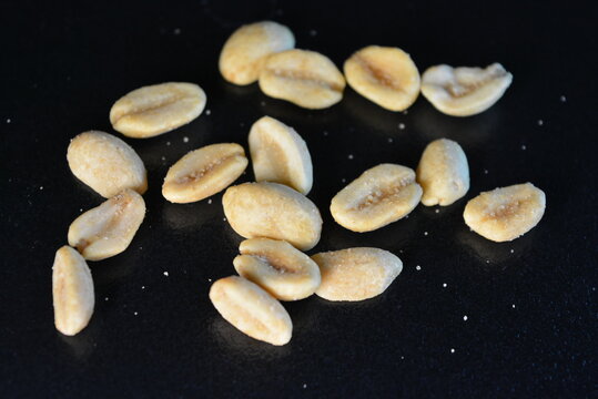 Healthy foods, health, nuts, salted toasted peanuts are scattered chaotically on a black background.