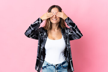 Young Romanian woman isolated on pink background covering eyes by hands and smiling