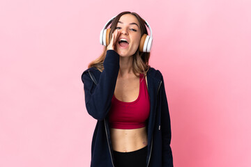 Young Romanian sport woman isolated on pink background shouting with mouth wide open