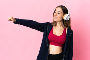 Young Romanian sport woman isolated on pink background giving a thumbs up gesture