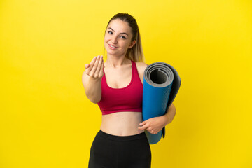 Young sport woman going to yoga classes while holding a mat inviting to come with hand. Happy that...