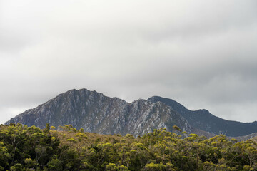 Naklejka premium Yacht sailing on the horizon near the beach on the ocean ina remote beautiful landscape, Tasmania, Australia and new zealand