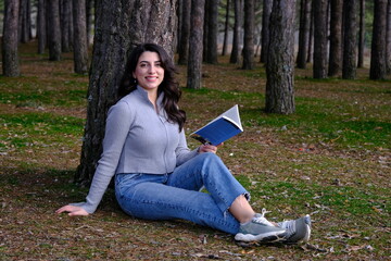 a woman lying on a tree and reading a book