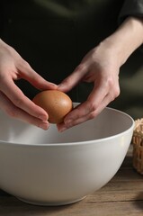 Making bread. Woman adding egg into dough at wooden table, closeup