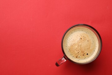 Fresh coffee in cup on red background, top view. Space for text