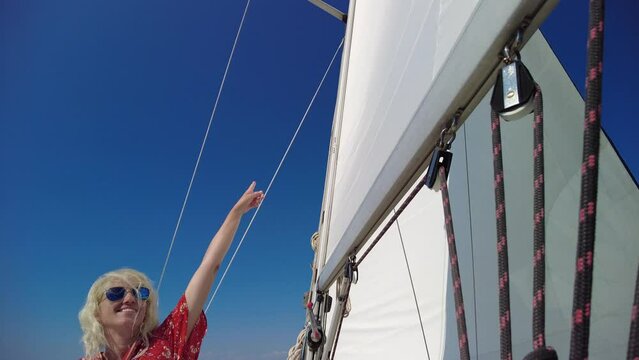 Girl in red looking the top sail of a sailboat. Navigating on a cruise tour In Telascica and Kornati national parks of Croatia. Adriatic Sea of Europe.