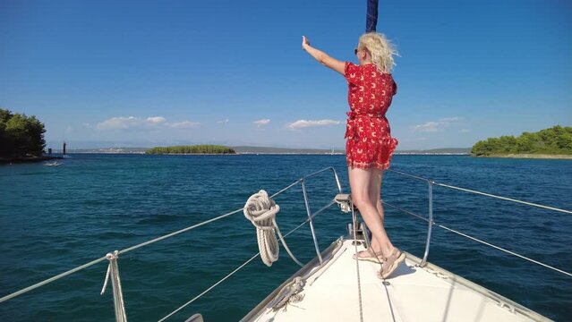Girl greeting with her hand on a sailboat to other boats. Boat trip to Telascica and Kornati national parks of Croatia. Adriatic Sea of Europe.