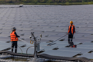 Worker Cleaning  floating solar panels or solar cell Platform system on the lake with brush and water. Worker cleaning solar modules in a Solar Energy Power Plant
