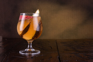 Glass with a drink on a brown background. Glass with slices of fruit. Drink on the table. Copy space.