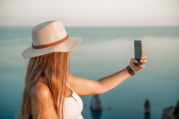 Selfie woman in hat, white tank top and shorts makes selfie shot mobile phone post photo social...
