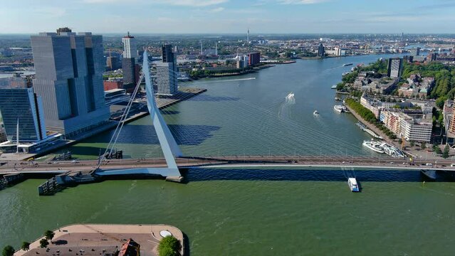 The Erasmusbrug ( Erasmus Bridge ) and modern architecture in Rotterdam, flying over the river Meuse in the Netherlands. Waterfront panoramic aerial view of the De Rotterdam towers in port area 4K