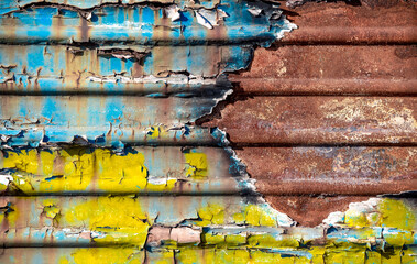 pattern rusty metal surface with remnants of blue and yellow paint paint