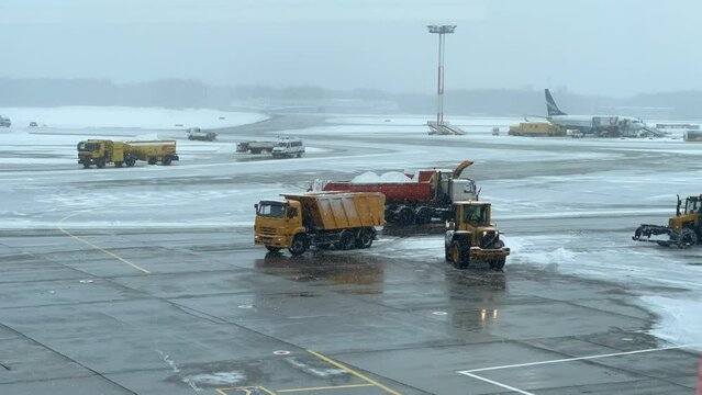 Time lapse of many tractors and dump trucks working on airways while cleaning it from snow in winter day
