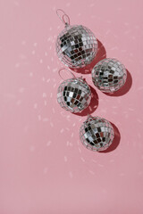 Small shining disco balls on pink background with blank copy space. Minimalist holiday party concept with aesthetic mirrored light reflections