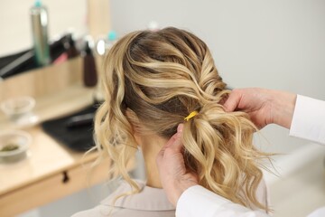 Fototapeta premium Hair styling. Professional hairdresser working with client indoors, closeup