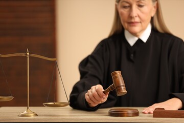 Judge striking mallet at wooden table indoors, selective focus