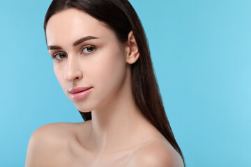 Naklejka premium Portrait of beautiful young woman on light blue background. Space for text