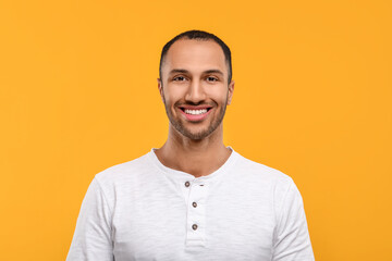 Portrait of smiling man with healthy clean teeth on orange background