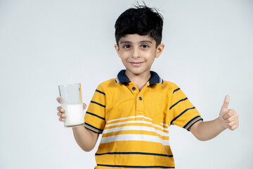 portrait of indian kid with glass of milk in hand on isolated background