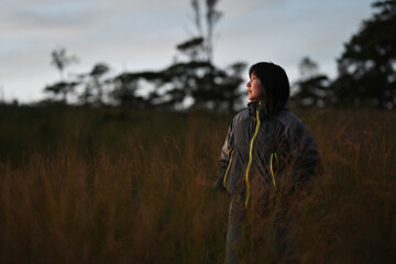 Young carefree female in trekking jacket cloth relaxing in summer meadow on the mountain, Summer delight and travel