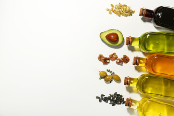 Vegetable fats. Different cooking oils in glass bottles and ingredients on white background, flat lay. Space for text