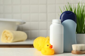 Baby cosmetic products, bath duck, brush and sponge on white table. Space for text