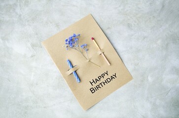 DIY birthday card.  A cake candle, a large match and a sprig of gypsophila on craft paper and a...