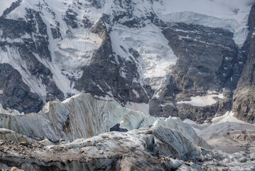 Melting glacier at the foot of a high mountain. Icefall with large blocks of ice.