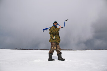 A man fisherman walks on the ice of a frozen lake.