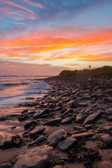 Fototapeta na wymiar Colorful sunrise view over a rocky beach shore.