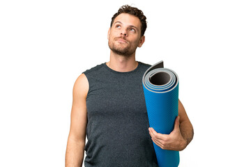 Young sport man going to yoga classes while holding a mat over isolated chroma key background...