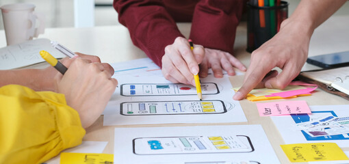 Close up of hands mobile phone app developer team meeting about screen display prototype layout for...