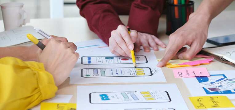 Close up of hands mobile phone app developer team meeting about screen display prototype layout for smartphone, ui, ux concept

