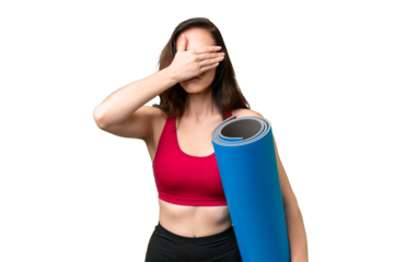Young sport woman going to yoga classes while holding a mat over isolated background covering eyes by hands. Do not want to see something