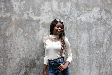 Portrait of beautiful young African American woman showing long black hair braided hairstyle while feeling happy and smiling in the city outdoor