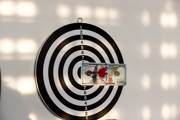Dollar bills pinned to a dart board with a dart business concept