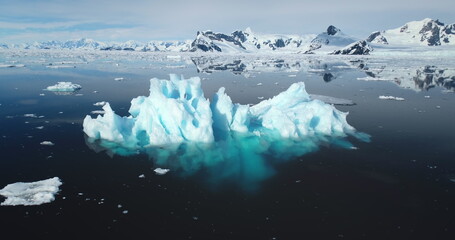 Blue melting ice float polar ocean in Antarctica. Snow covered mountains in background. Ecology,...