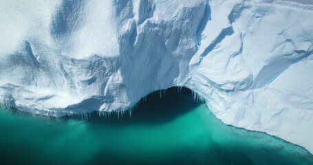 Melting Antarctic glacier ice cave in turquoise ocean water. Huge high iceberg, snow ice wall with...