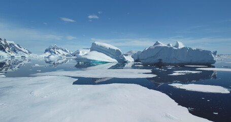 Icebergs from melting glacier float in icy ocean at sunny day. Global warming and climate change concept. Cinematic ecology scene. Beauty of wild untouched Arctic nature. Low angle drone shot