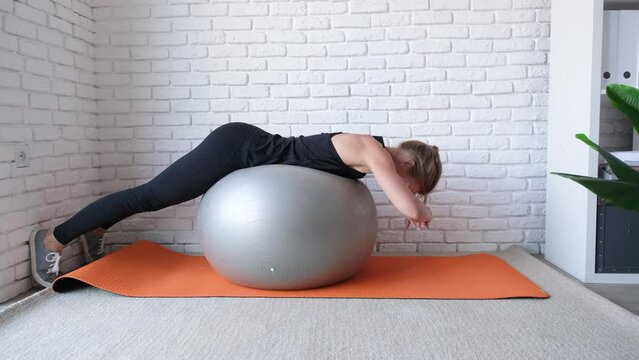 Fitness, sports and healthy lifestyle. young woman working out at home with stability ball or fitness bal. Home training