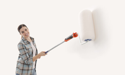 Happy woman painting walls with a roller