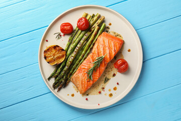 Tasty grilled salmon with asparagus, tomatoes and spices on light blue wooden table, top view