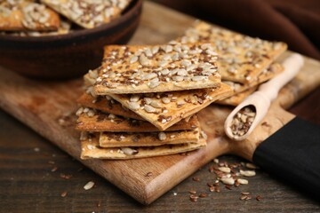 Cereal crackers with flax, sunflower and sesame seeds on wooden table, closeup