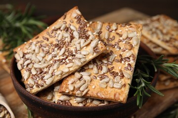 Cereal crackers with flax, sunflower, sesame seeds and rosemary on table, closeup