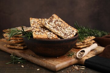 Cereal crackers with flax, sunflower, sesame seeds and rosemary on wooden table