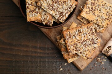 Cereal crackers with flax, sunflower and sesame seeds on wooden table, top view. Space for text